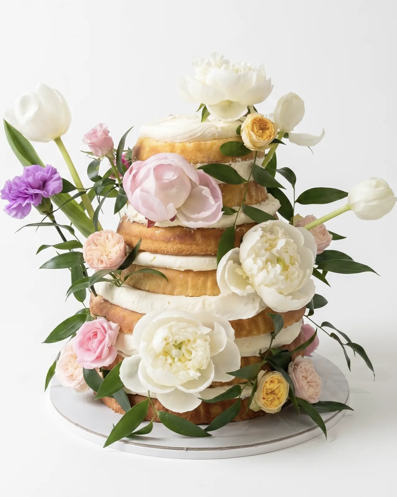 Naked-style engagement cake layered with fresh peonies, roses and tulips, a custom cake by Cakes By Vjollca in Pristina, Kosovo