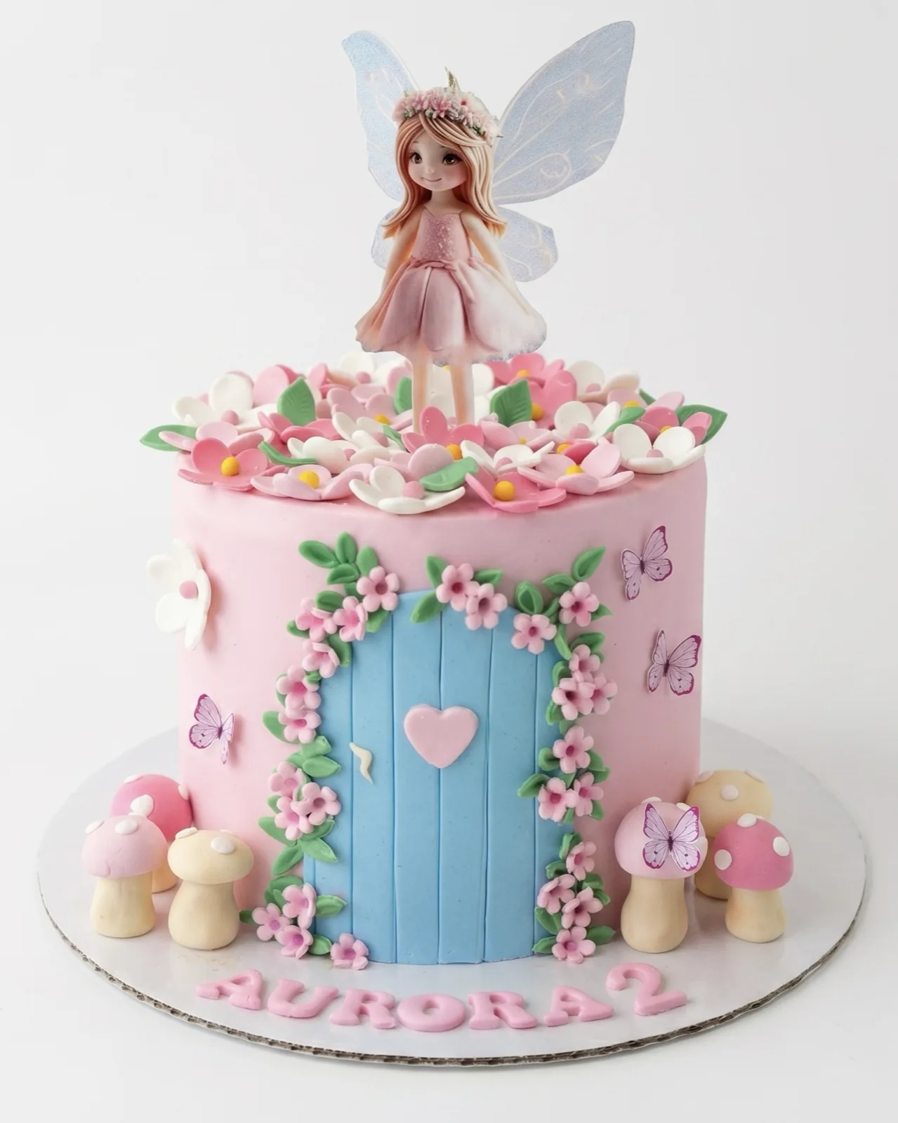 Pink fairy garden birthday cake with a fairy topper, flower door and toadstools, a custom cake by Cakes By Vjollca in Pristina, Kosovo