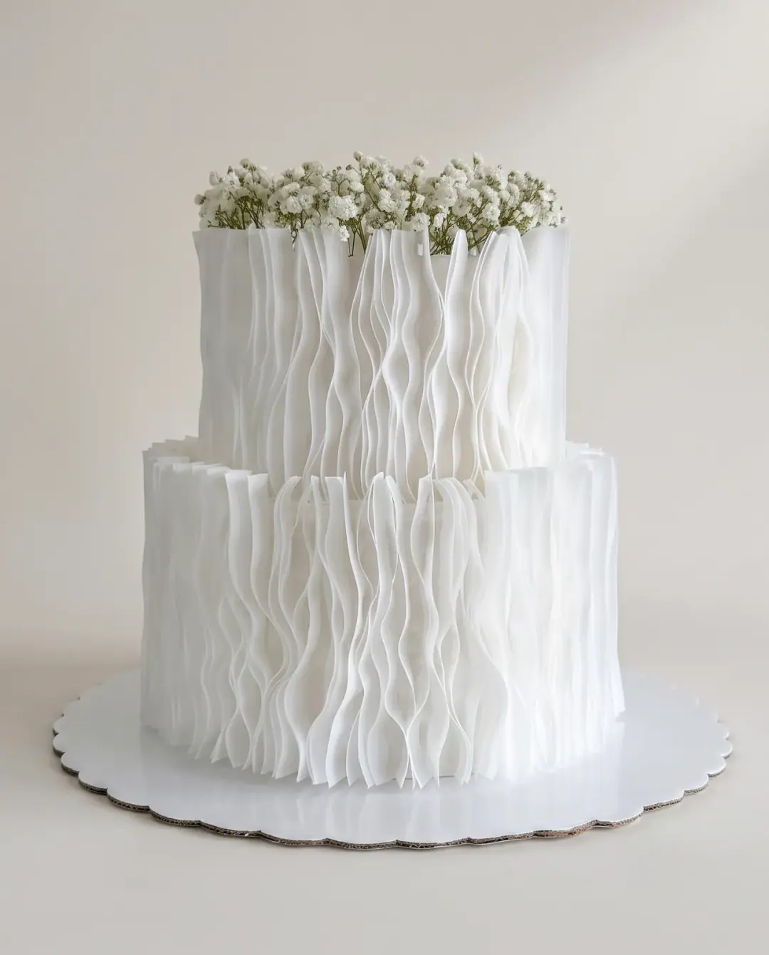 Two-tier white engagement cake wrapped in rippled wafer paper with baby's breath on top, a custom cake by Cakes By Vjollca in Pristina, Kosovo