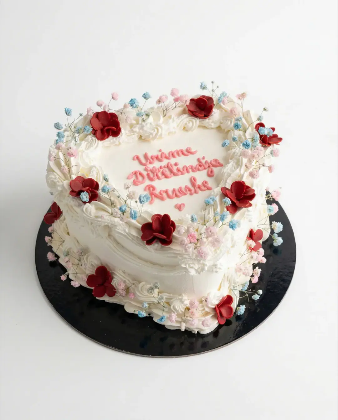 White heart cake with red and pink sugar blossoms and a piped birthday wish, a custom cake by Cakes By Vjollca in Pristina, Kosovo