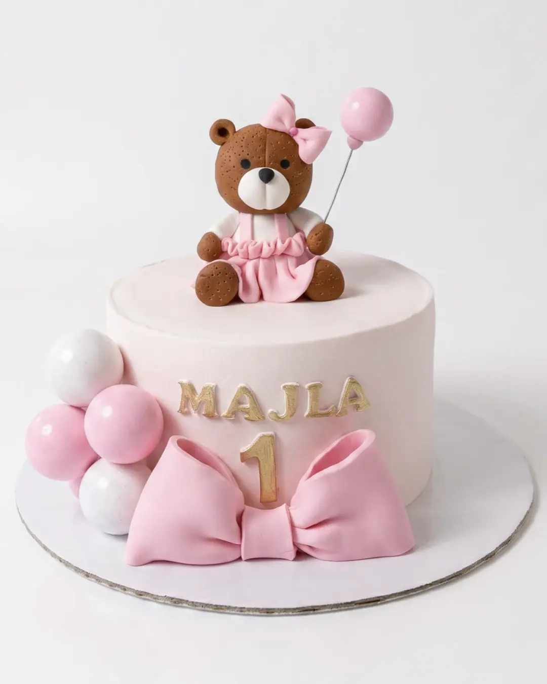 Blush first birthday cake with a teddy bear, pink bow and balloons, a custom cake by Cakes By Vjollca in Pristina, Kosovo