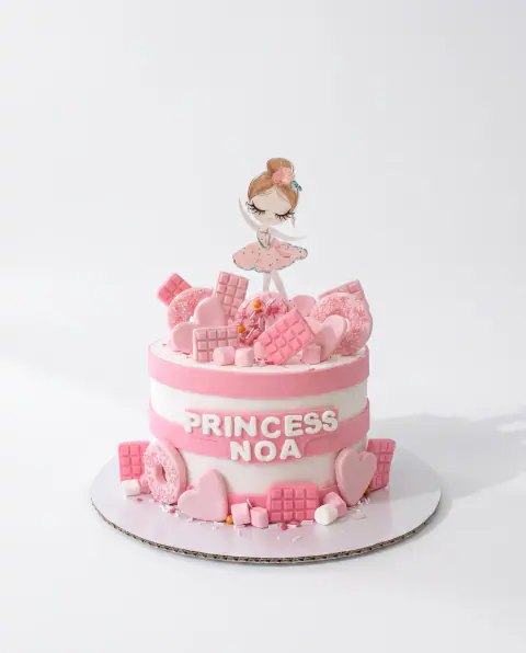 Pink and white princess birthday cake with a ballerina topper and fondant chocolate bars, doughnuts, hearts and marshmallows, a custom cake by Cakes By Vjollca in Pristina, Kosovo