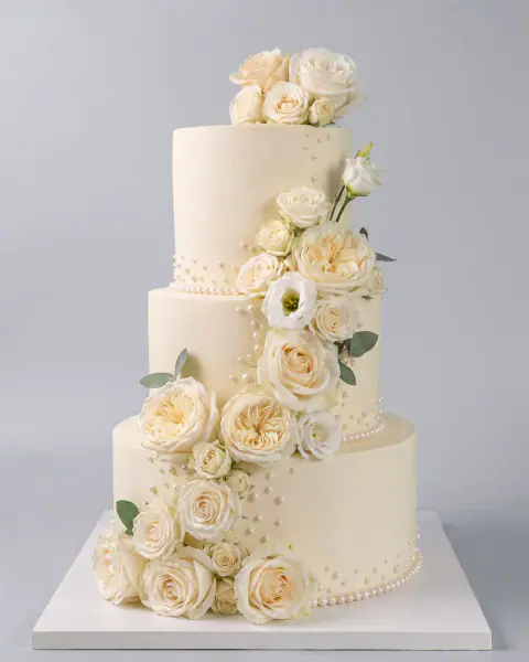 Torte dasme me tre kate në fildish me kaskadë diagonale trëndafilash kremi, lisiantus dhe perla sheqeri, torte me porosi nga Cakes By Vjollca në Prishtinë