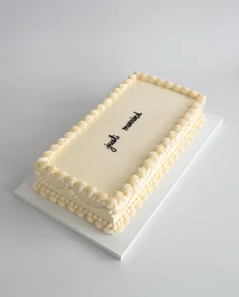 Rectangular ivory buttercream wedding cake with piped shell borders and swags and 'just married' in black script on top, a custom cake by Cakes By Vjollca in Pristina, Kosovo